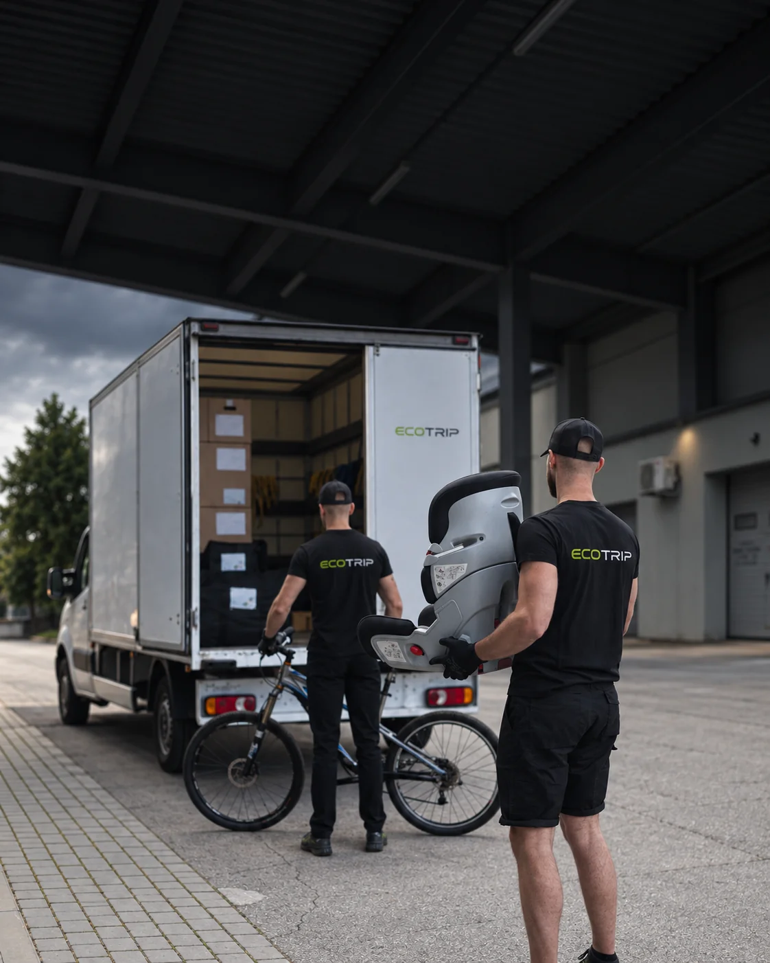 Two EcoTrip staff beside a vehicle preparing to transport a bicycle and child car seat. Illustration.